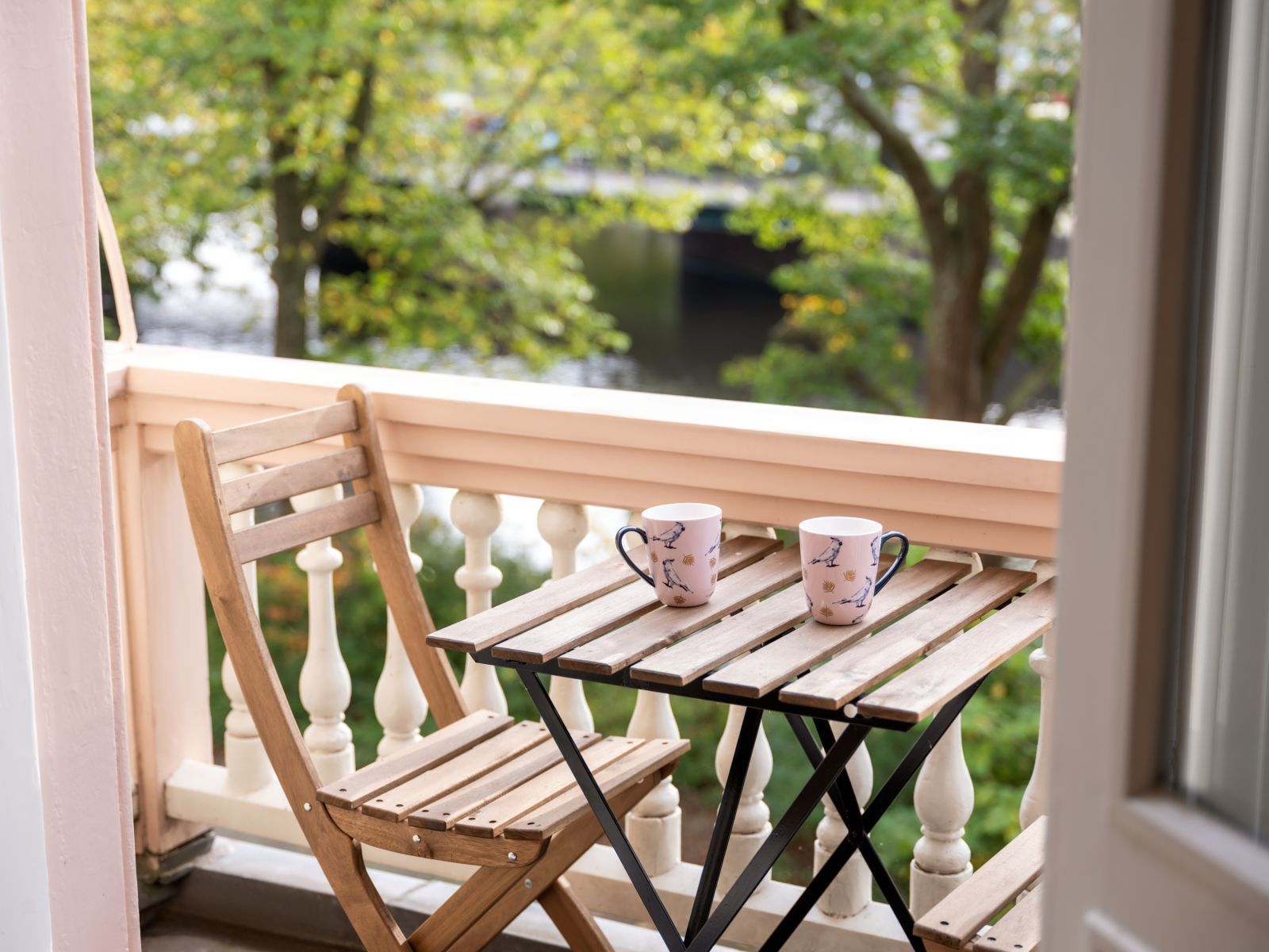 Two cups are sitting on a wooden table on a balcony in Canal Suite.