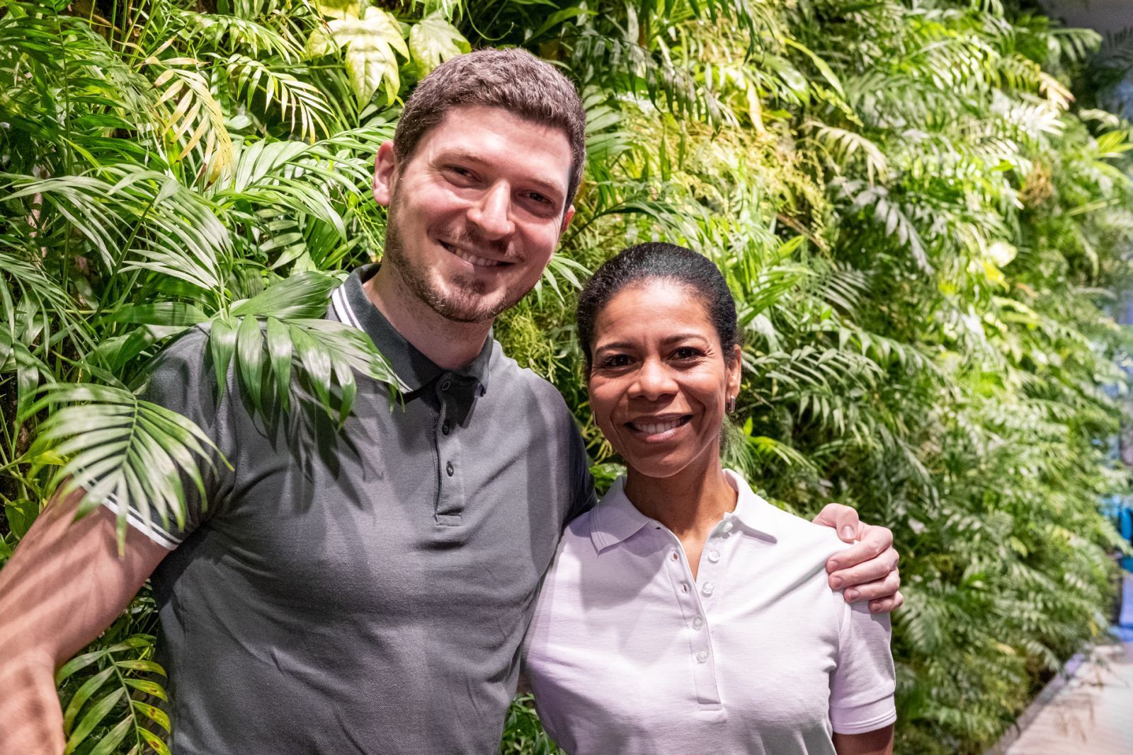 Massage staff are posing for a picture in front of a green wall.
