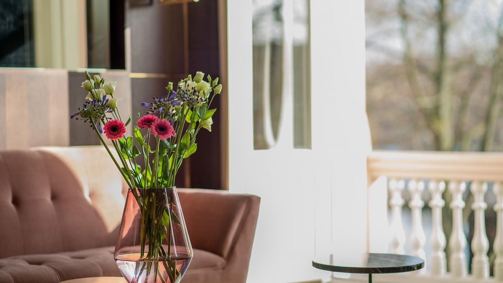 A vase of flowers is sitting on a table in a living room next to a couch. In the Canal Suite.