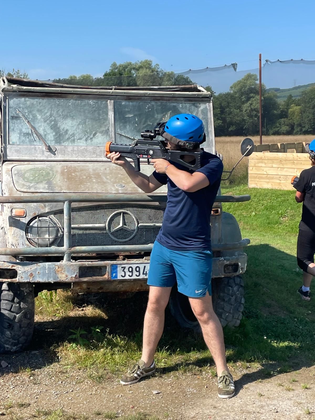 Homme avec un pistolet de laser game devant une voiture