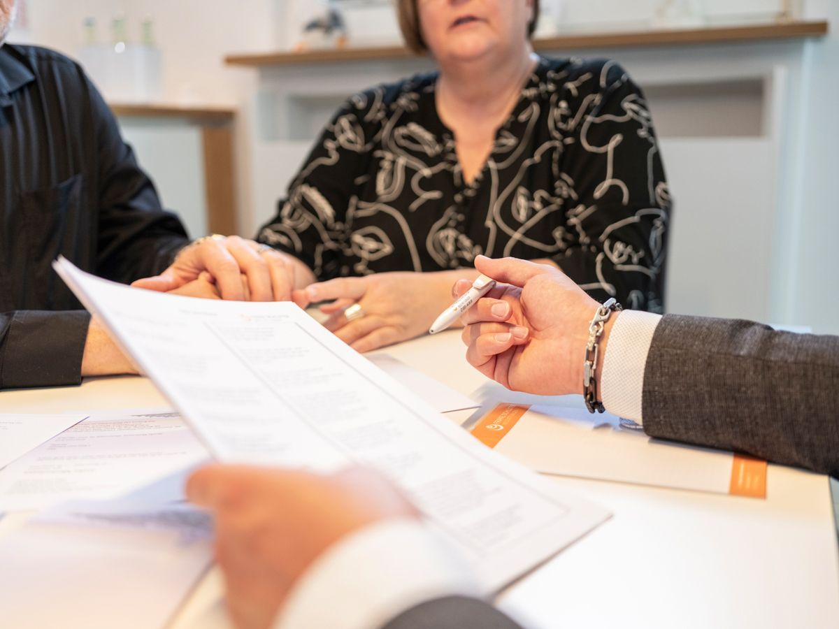 Eine Gruppe von Leuten sitzt an einem Tisch und schaut auf ein Blatt Papier.
