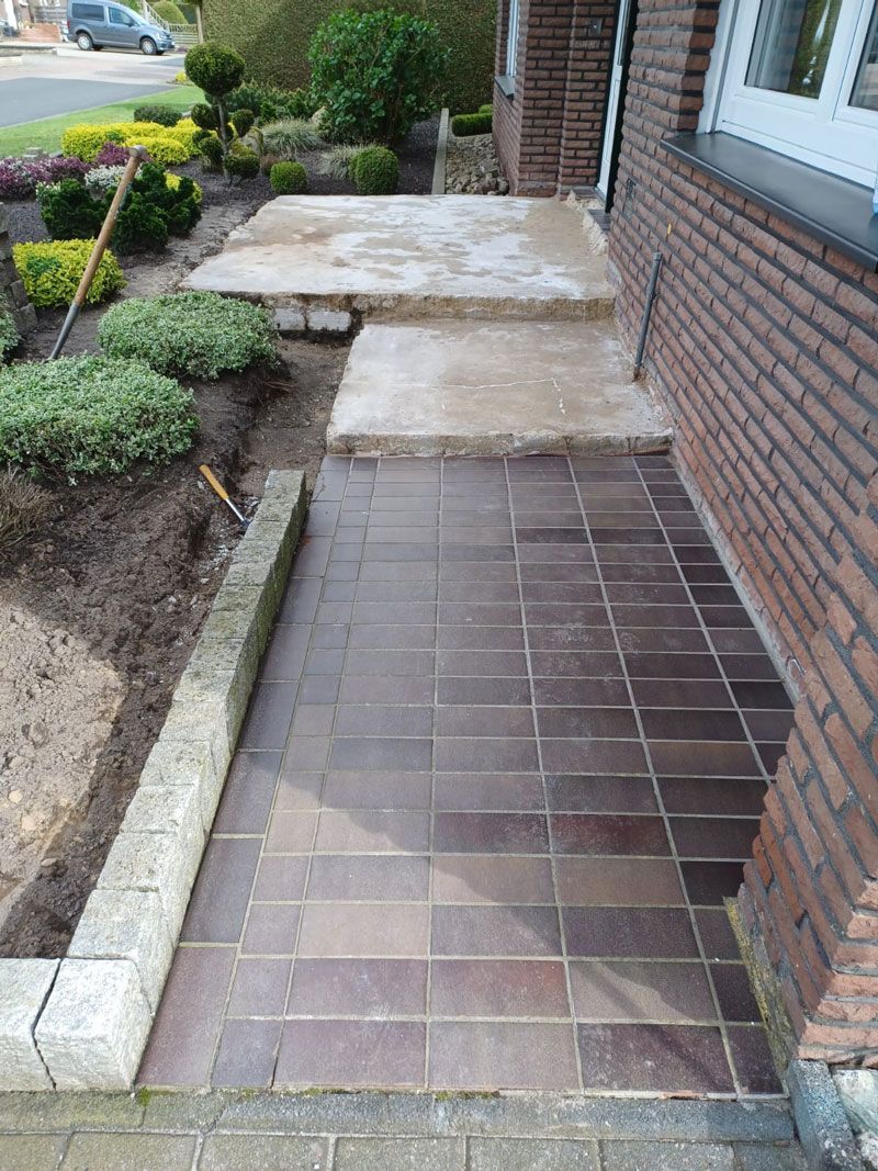 Ein gemauerter Gehweg mit Stufen führt zu einem Haus hinauf.