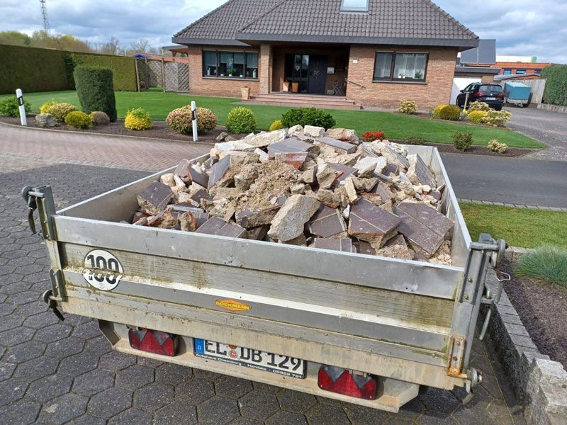 Vor einem Haus steht ein mit Steinen beladener Anhänger.