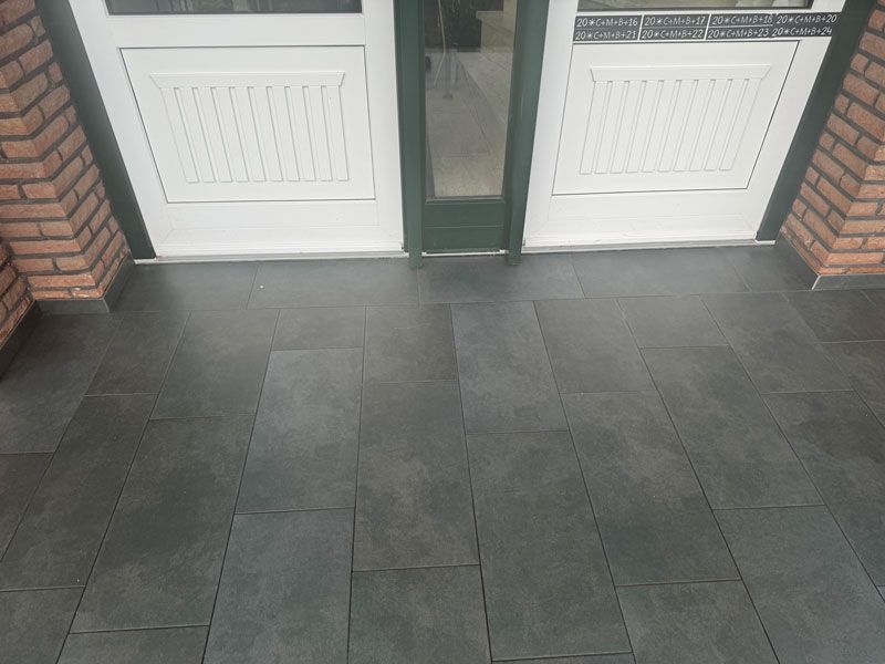 Ein schwarzer Fliesenboden mit einer weißen Tür im Hintergrund