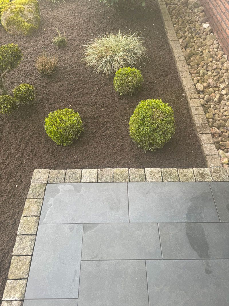 Ein Innenhof mit Ziegelumrandung und einem Garten im Hintergrund.