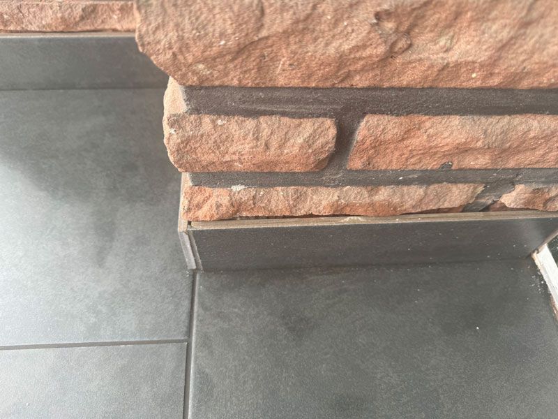 Eine Nahaufnahme einer Ziegelwand neben einem gefliesten Boden.