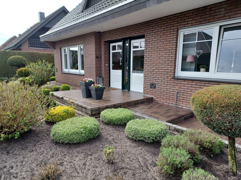 Ein Backsteinhaus mit Veranda und davorliegendem Garten.