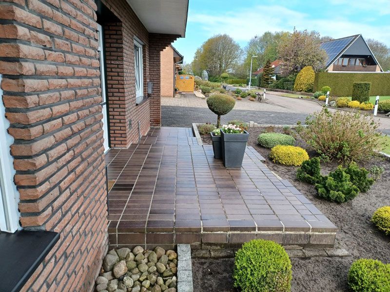 Ein Backsteinhaus mit einer Veranda und einem Garten davor