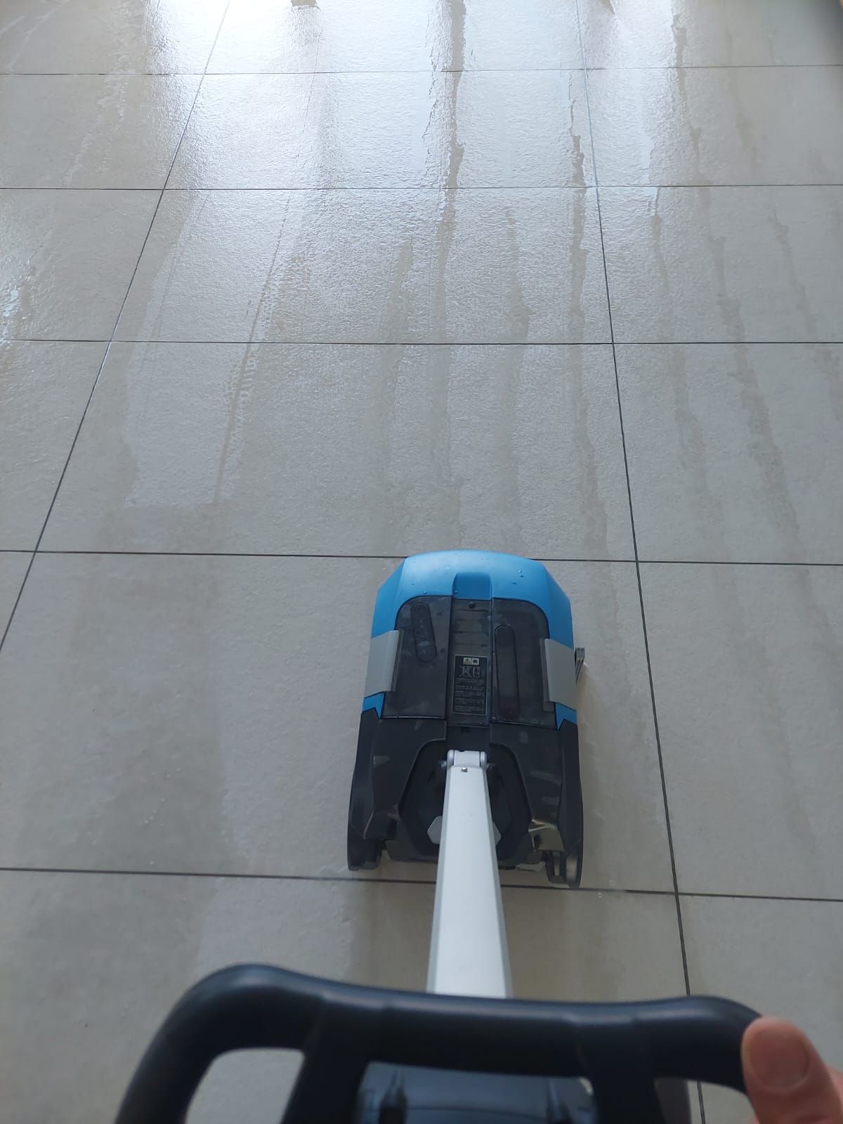 Eine Person reinigt mit einem Wischmopp einen Fliesenboden