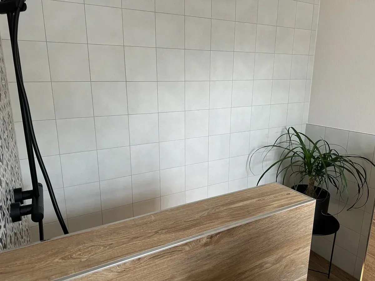 Ein Badezimmer mit weißen Fliesen und einer Holzwaschtischplatte.