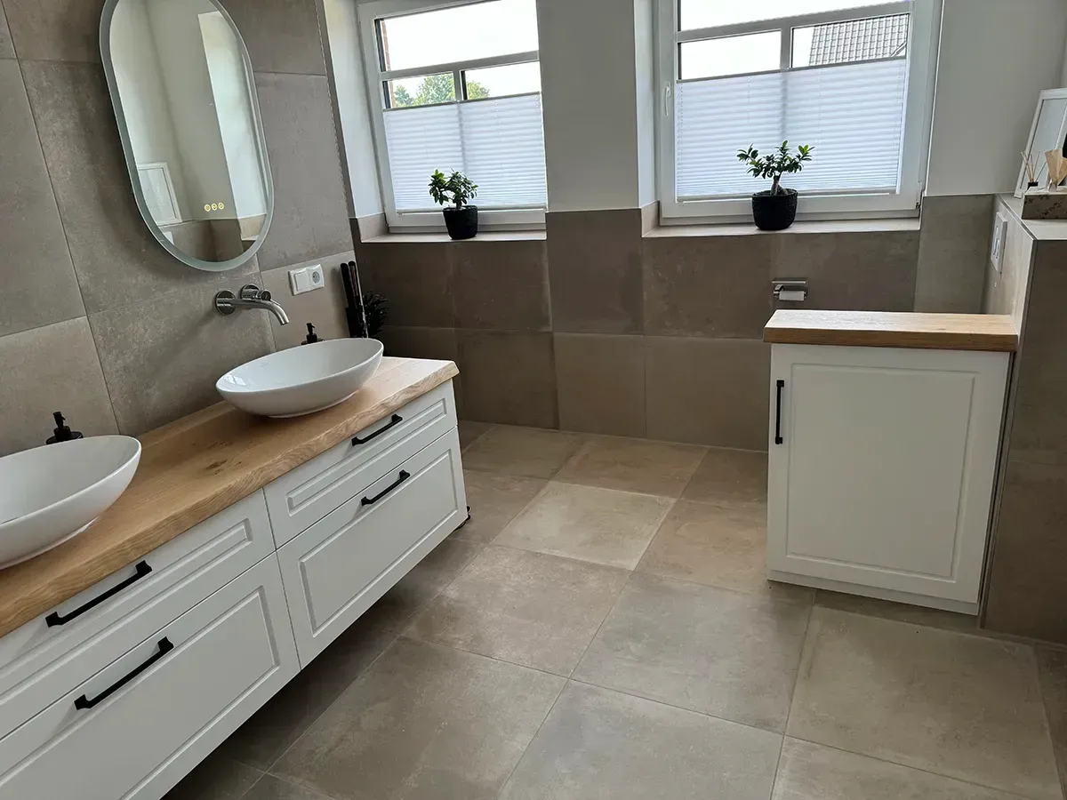 Ein Badezimmer mit zwei Waschbecken, einem Spiegel und einem Fenster.