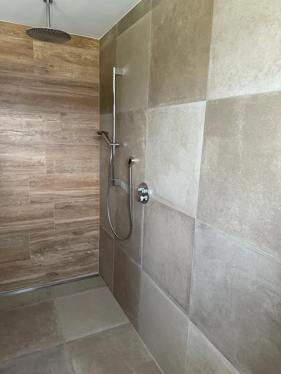 Ein Badezimmer mit ebenerdiger Dusche und Holzwand.