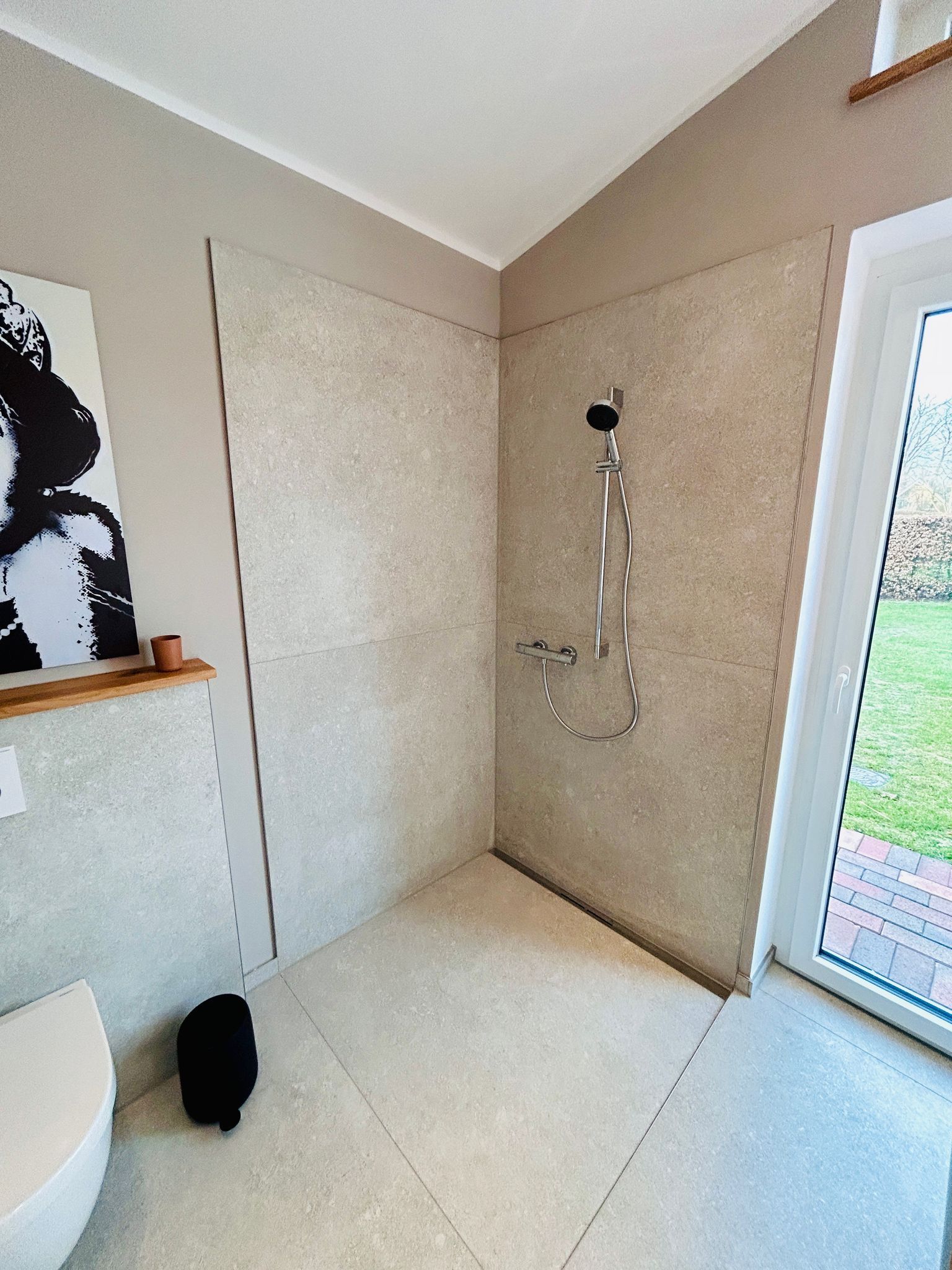 Ein Badezimmer mit ebenerdiger Dusche und Toilette.