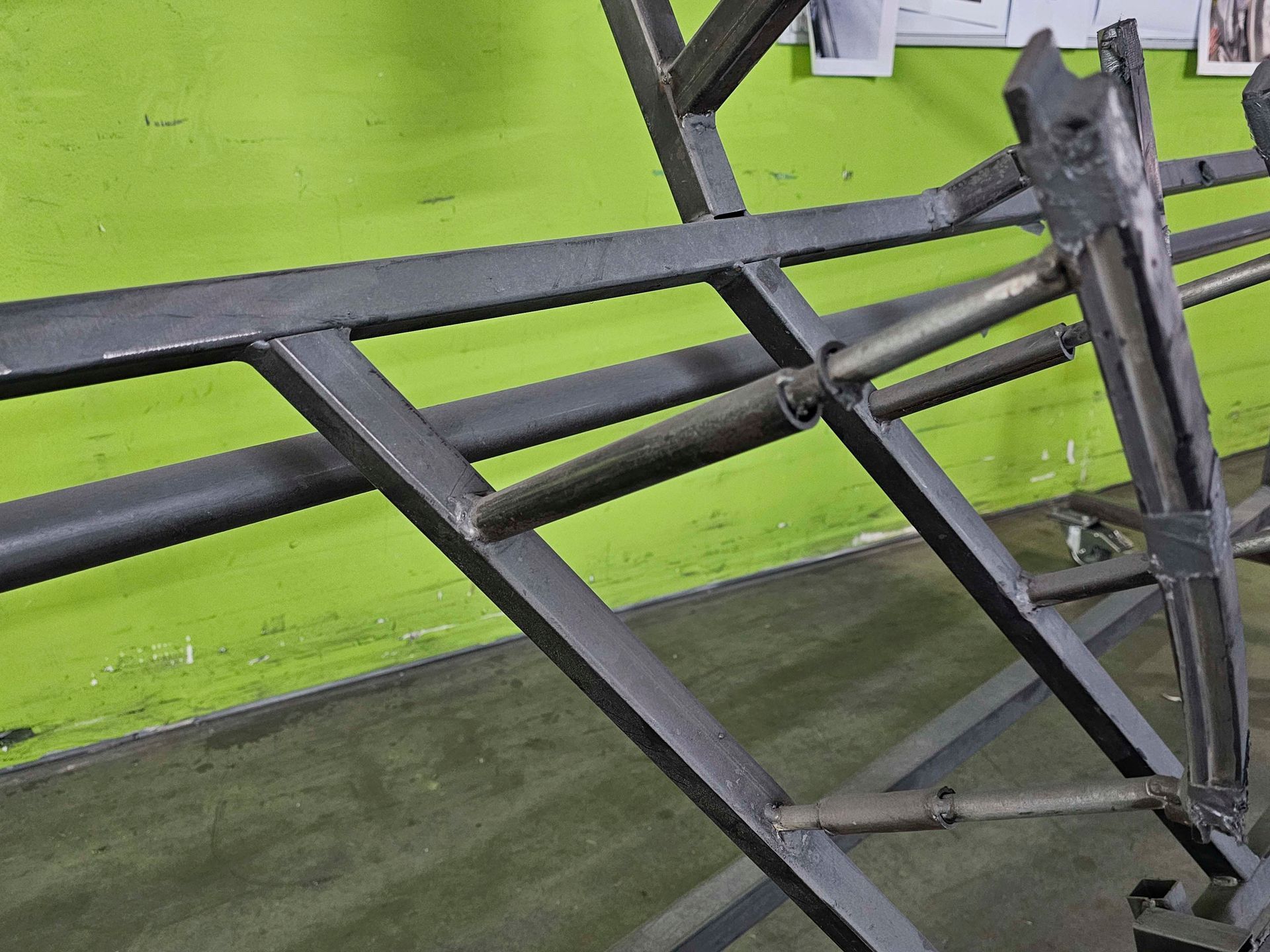 Vor einer grünen Wand steht eine Metallkonstruktion