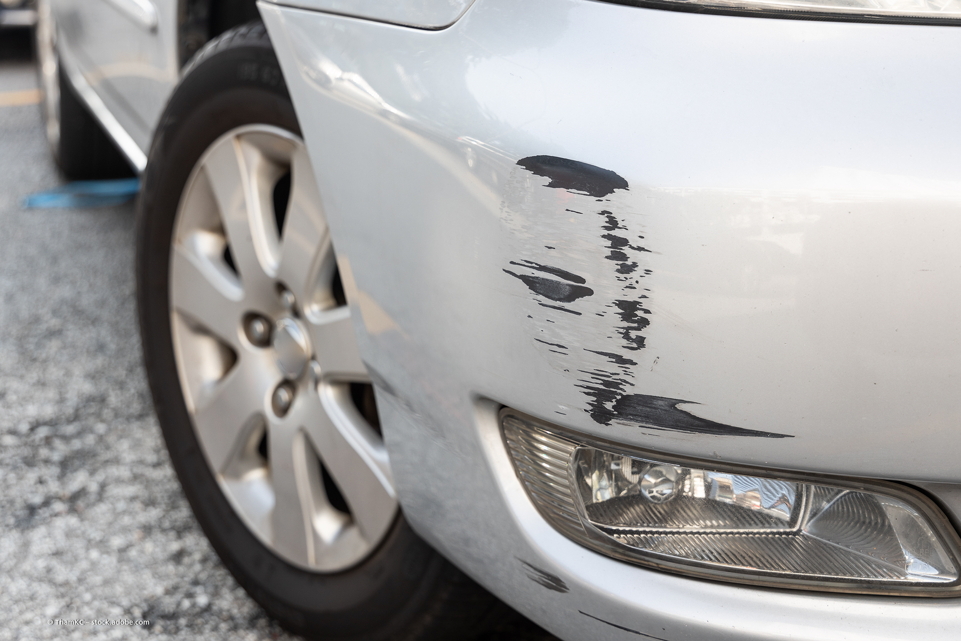Eine Person glättet mit einem Abzieher eine Schutzfolie auf der Motorhaube eines schwarzen Autos.