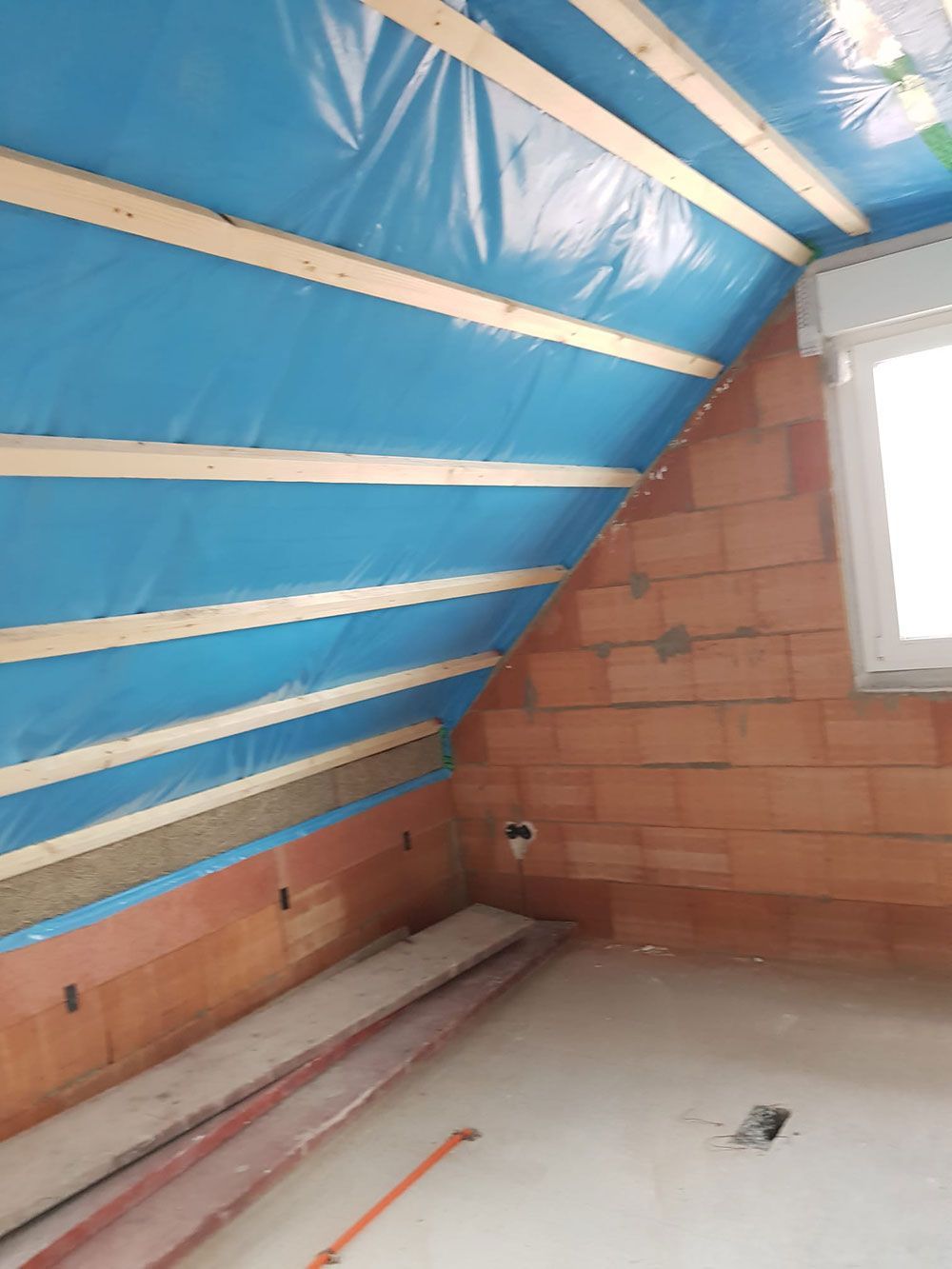 Ein Raum mit einer Ziegelwand und einer blauen Plane an der Decke.