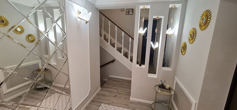 Ein Flur mit einer Treppe und einem Spiegel an der Wand.