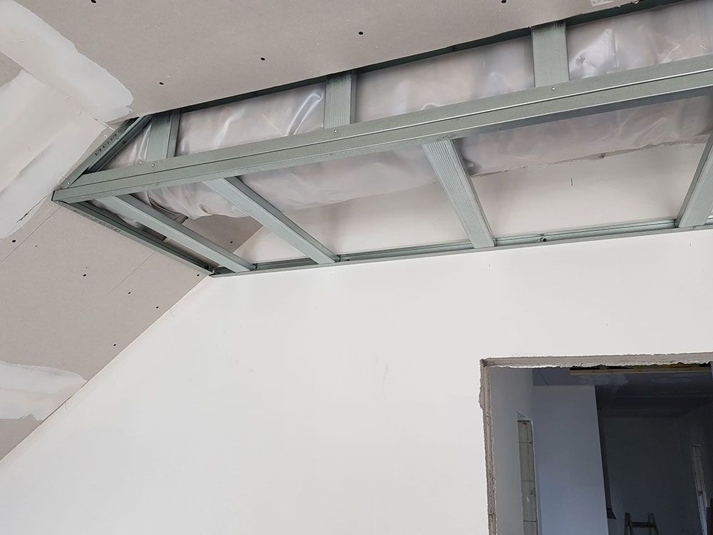 In einem Raum mit einer Tür wird eine Decke eingebaut.