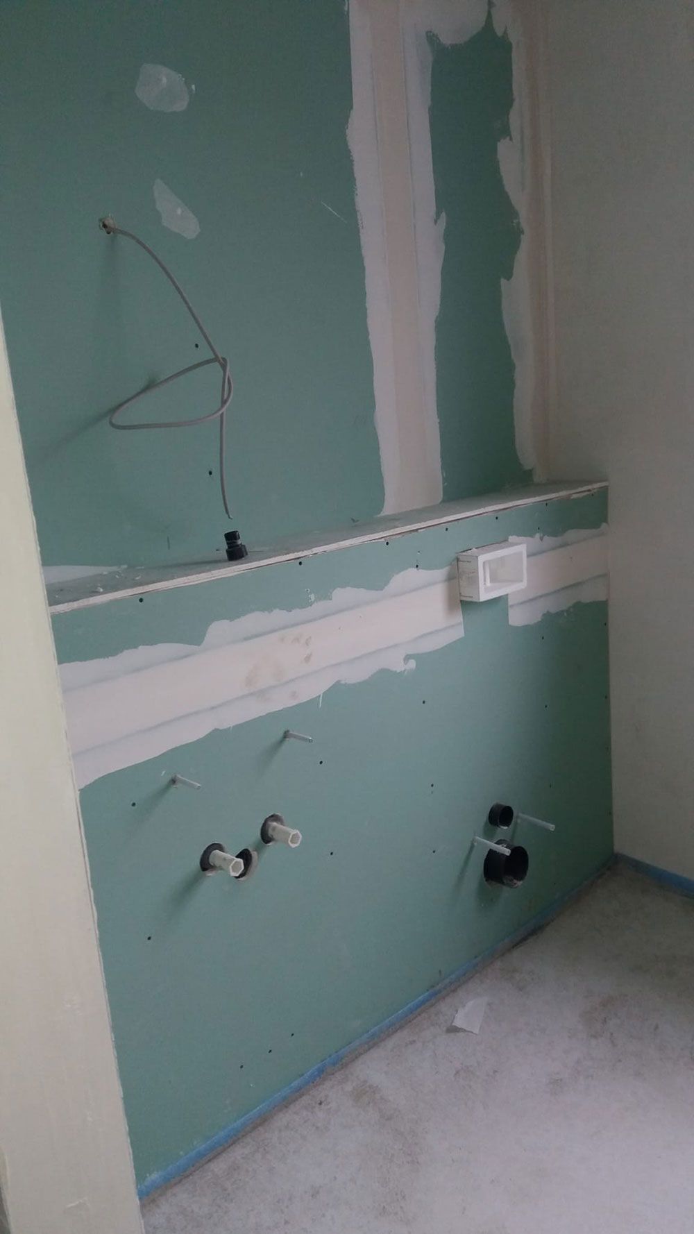 Ein im Bau befindliches Badezimmer mit einer grünen Wand und weißen Wänden.