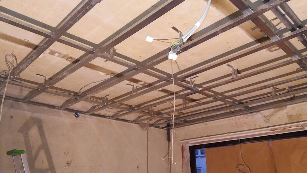 Ein Raum mit einer Leiter und einer Decke, die gerade renoviert wird.