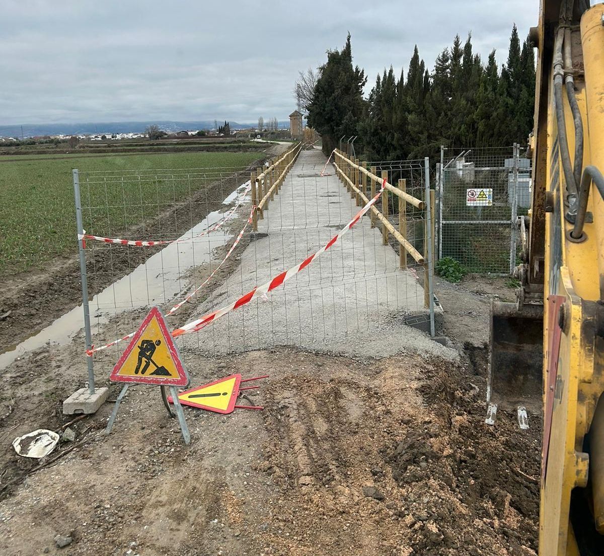 Un sitio de construcción con un cartel amarillo y una excavadora amarilla.