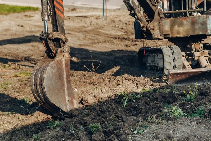 Una excavadora está cavando un hoyo en el suelo en un sitio de construcción.