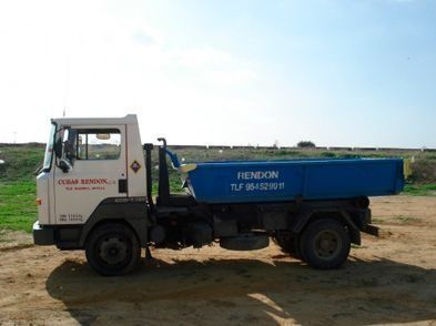 Un camión de volteo está estacionado en un campo de tierra.