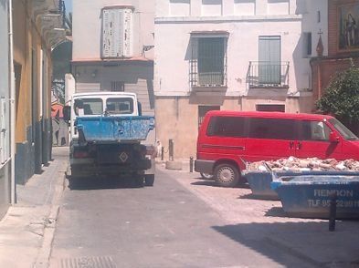 Un camión volquete azul está estacionado al lado de una camioneta roja