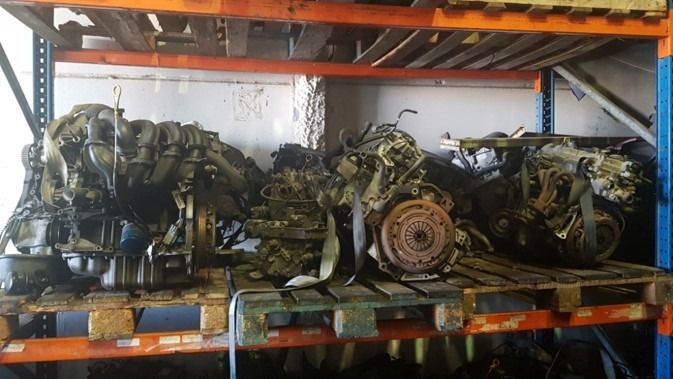 Un montón de motores están sobre paletas en un almacén.