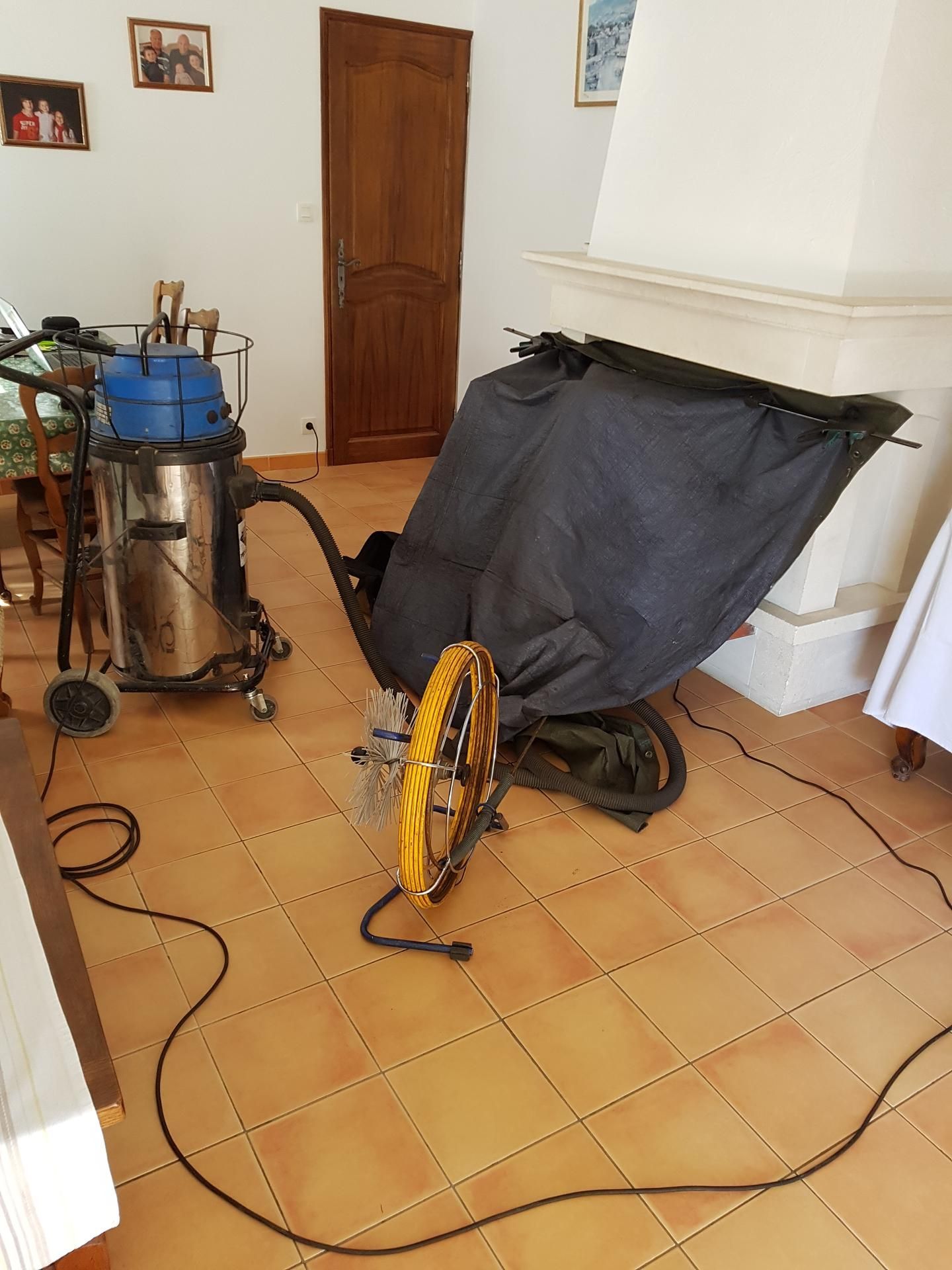 Aspirateur de chantier et kit de ramonage devant une cheminée