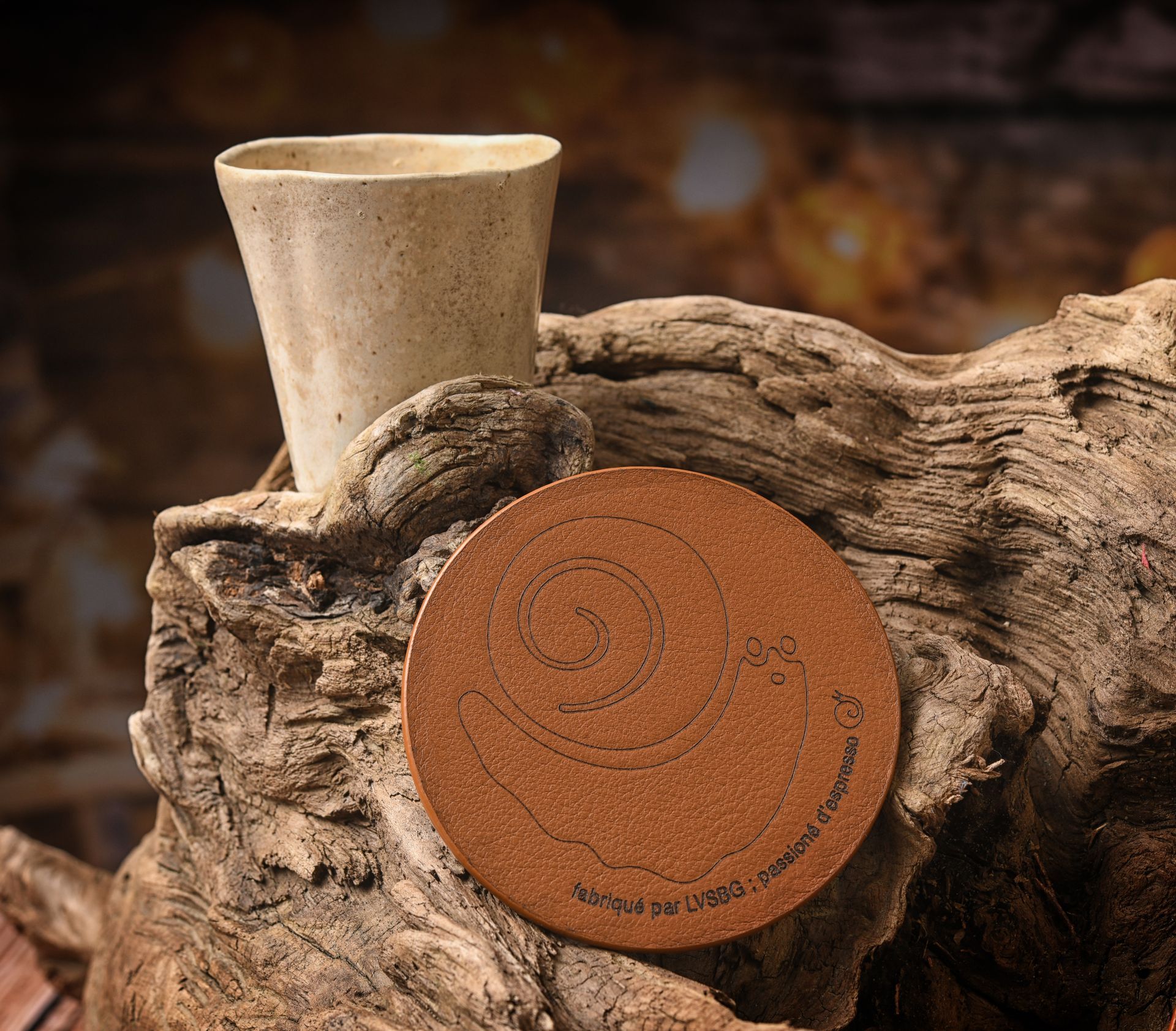 Tasse et sous-verre en céramique sur une surface en bois patiné, lumière naturelle.