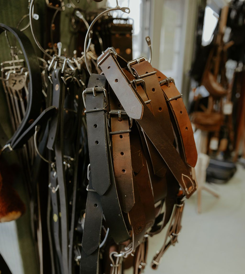 Des sangles en cuir avec boucles sont exposées dans un magasin.
