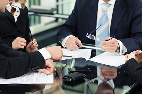 Un grupo de gente de negocios está sentado alrededor de una mesa teniendo una reunión.