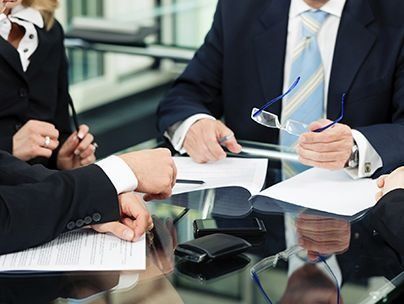 Un grupo de hombres de negocios están sentados alrededor de una mesa mirando papeles.