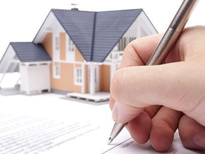 Una persona está escribiendo en un trozo de papel delante de una casa modelo.