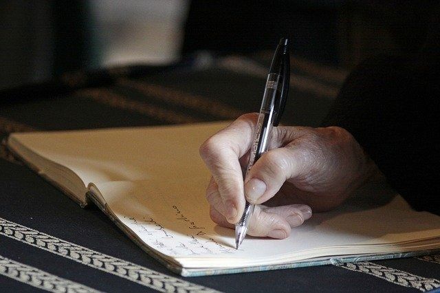 Una persona está escribiendo en un cuaderno con un bolígrafo.