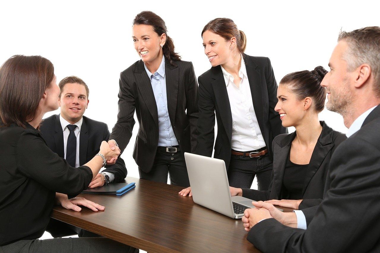 Un grupo de hombres de negocios están sentados alrededor de una mesa con una computadora portátil.