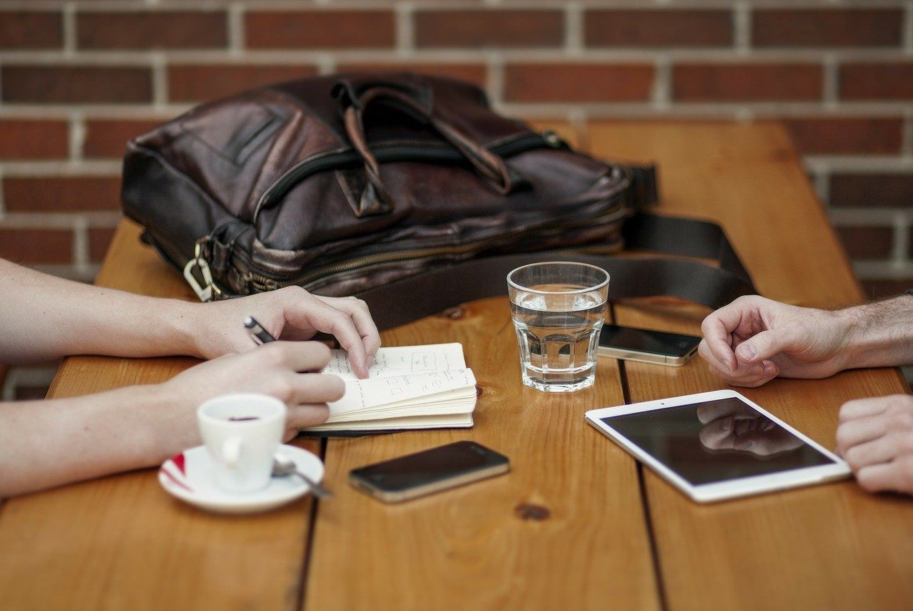 Dos personas están sentadas en una mesa con una tableta y una taza de café.
