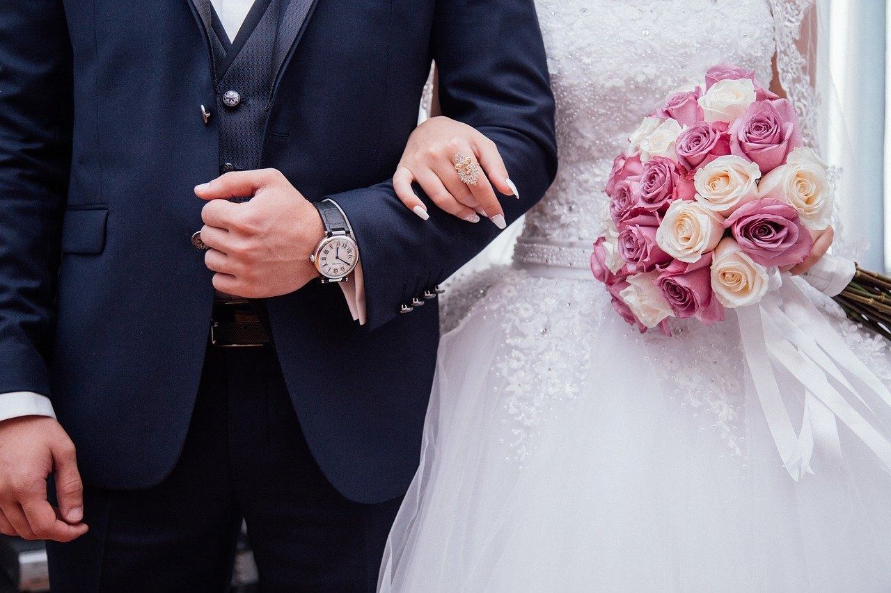 Una novia y un novio están parados uno al lado del otro y la novia sostiene un ramo de flores.