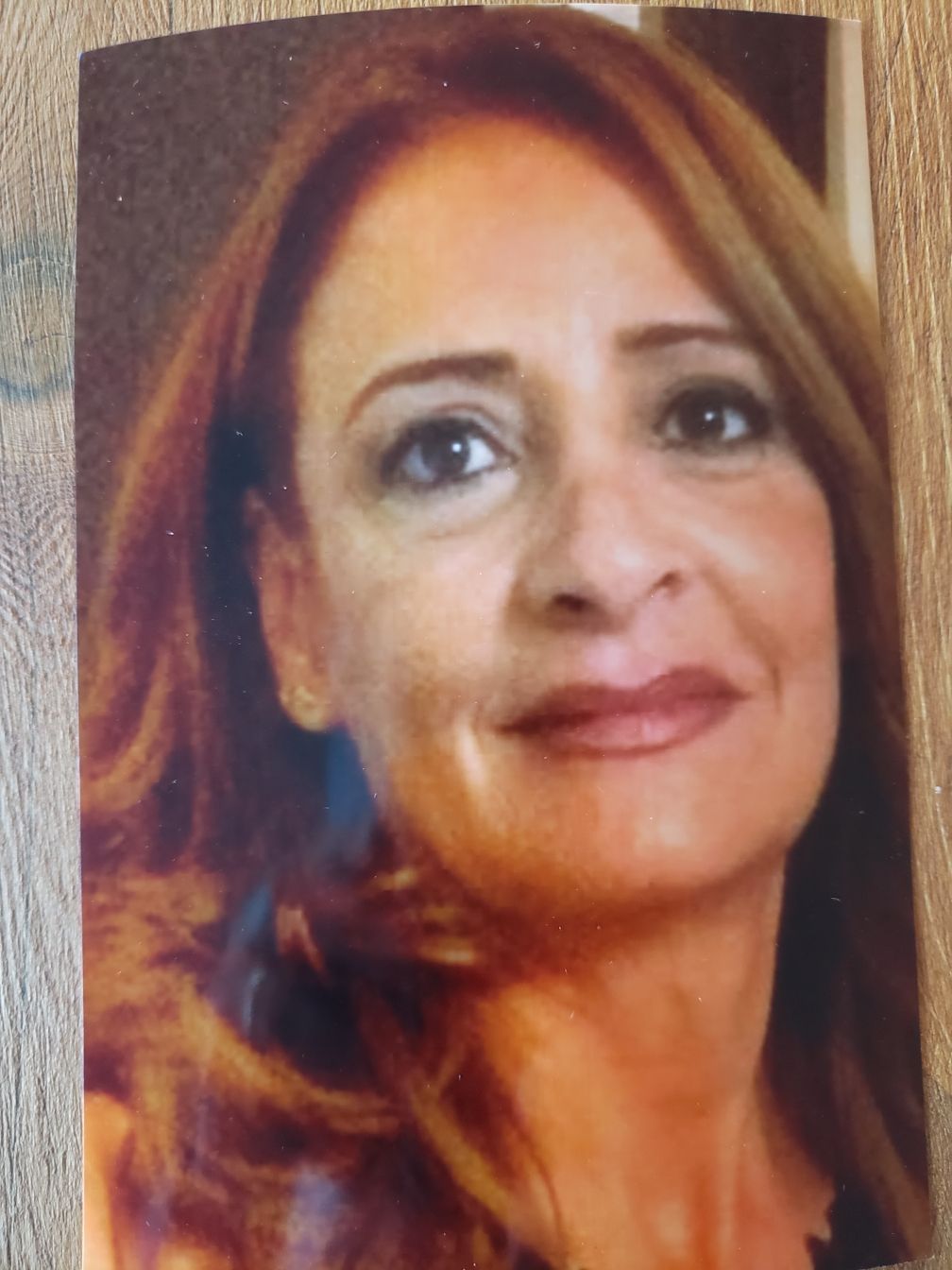 Une femme coiffée d'un béret rouge affiche un large sourire. En extérieur, en journée.