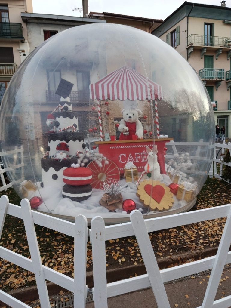 Boule à neige géante décorée pour Noël avec un ours polaire. Clôture blanche.