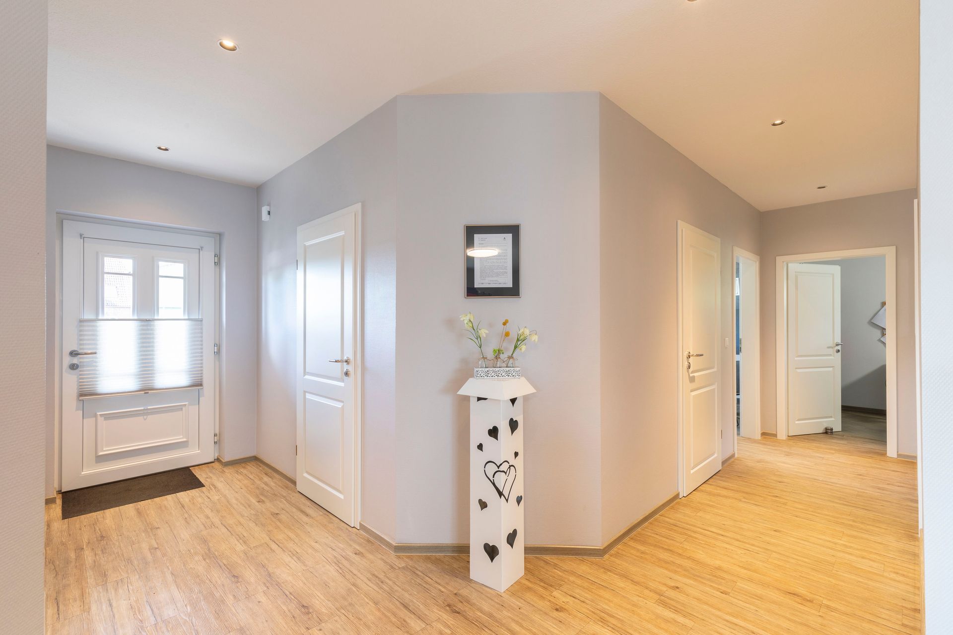 Ein Flur mit einer Blumenvase auf einem Podest in der Ecke.