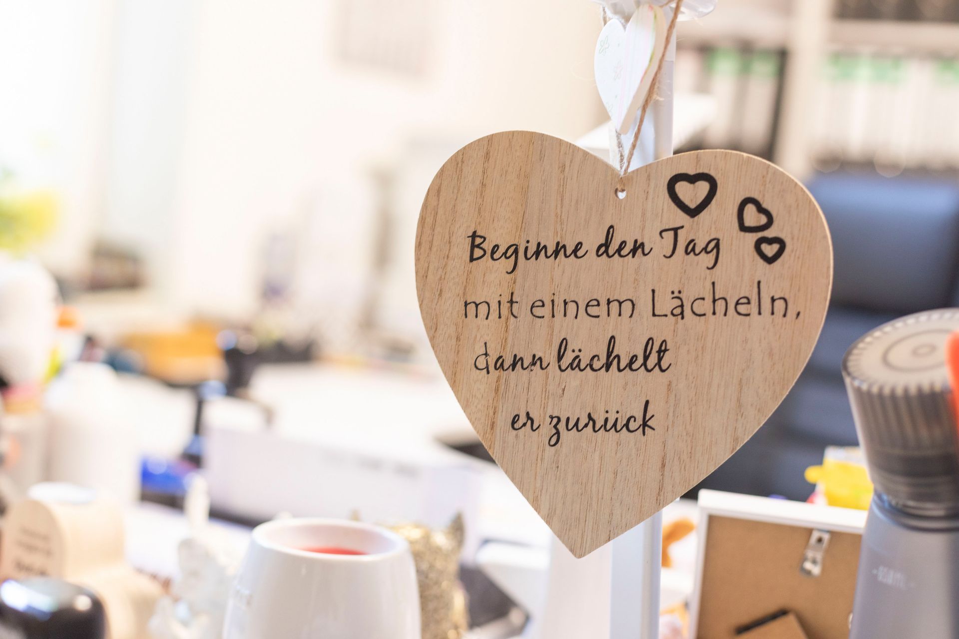 An einer Schnur hängt ein Holzherz mit einem Zitat darauf.