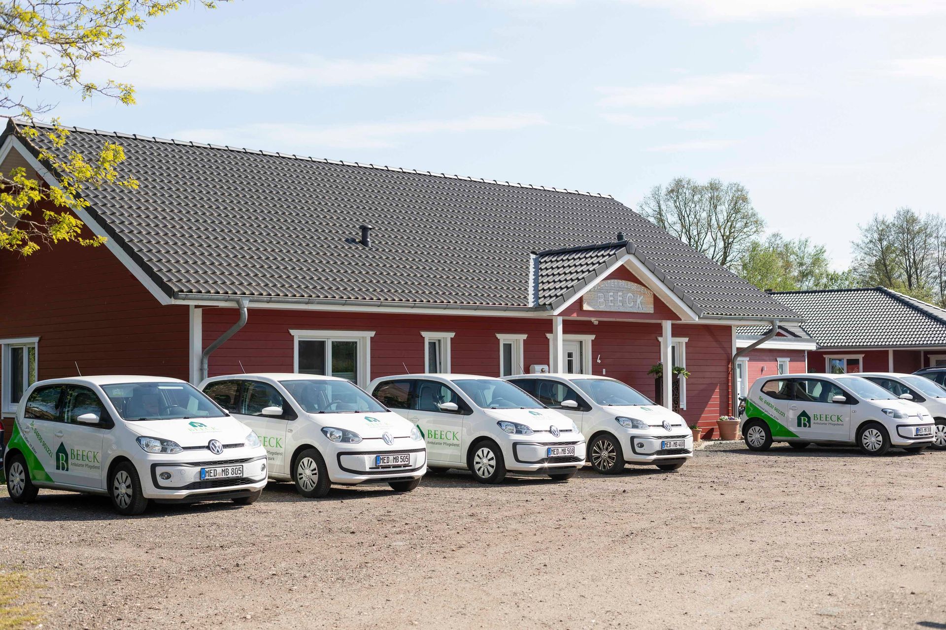 Eine Reihe weißer Lieferwagen parkt vor einem roten Gebäude.