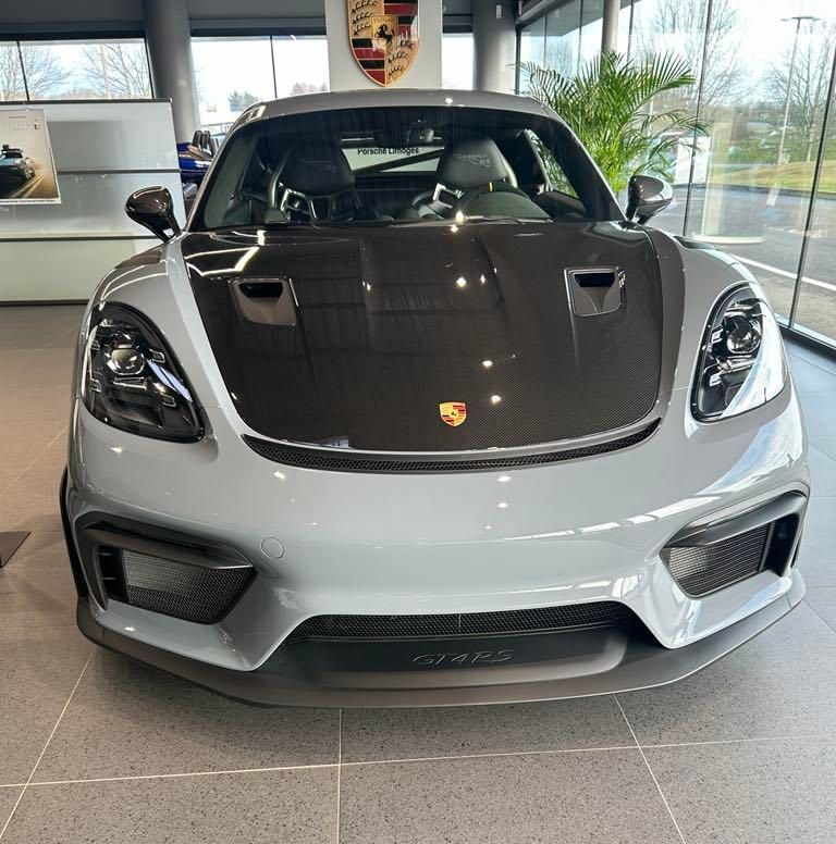 Porsche sport grise avec un capot gris foncé exposée dans un showroom.