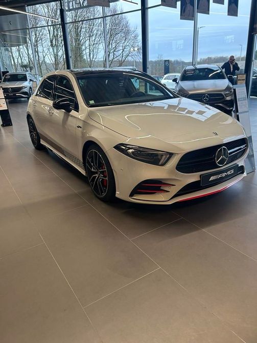 Berline Mercedes-Benz blanche dans un showroom, vue de face en angle.