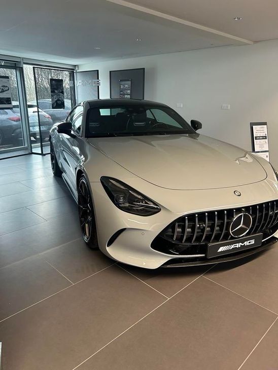 Voiture de sport Mercedes blanche exposée dans un showroom près d'une entrée vitrée