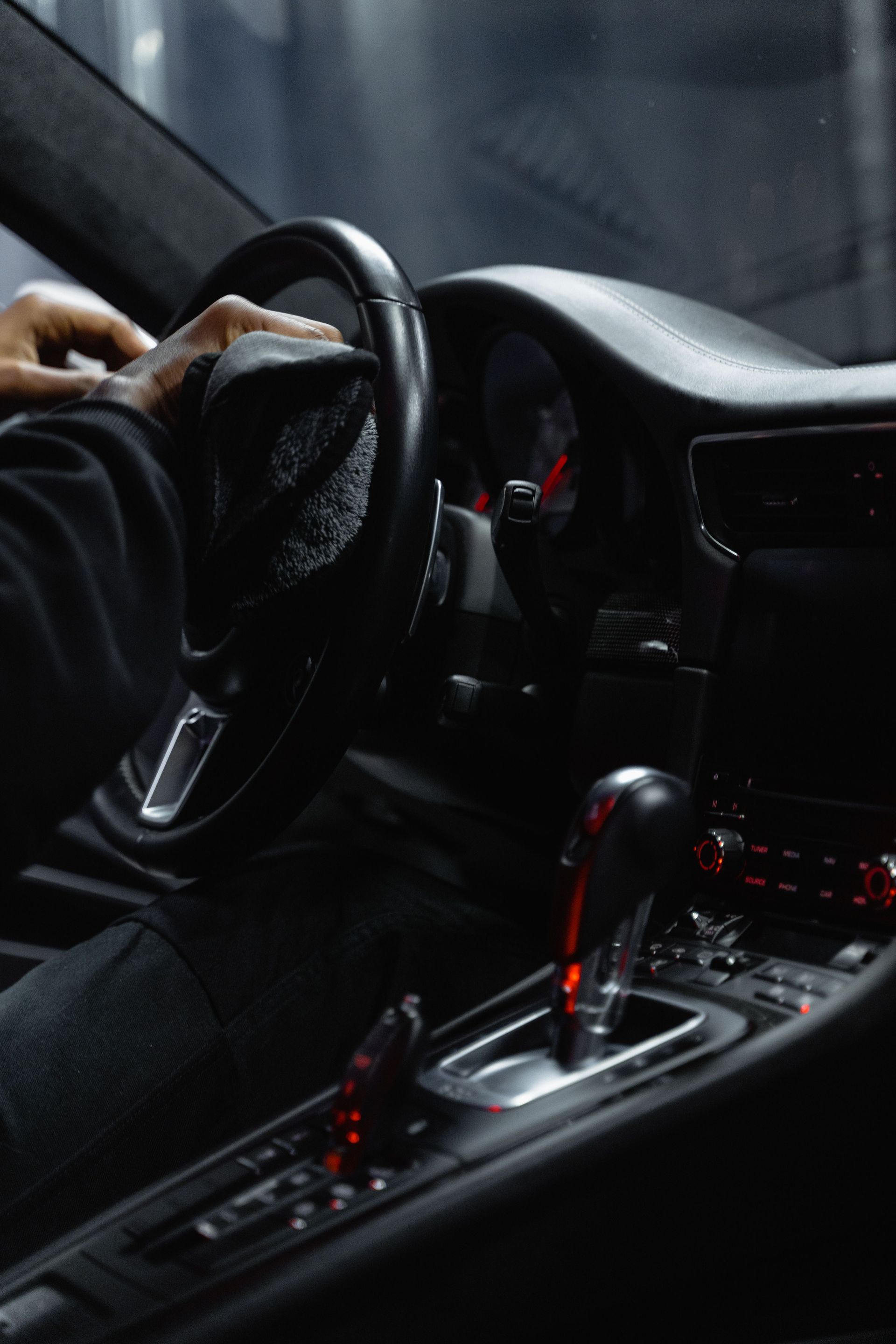 Mains d'un conducteur sur le volant à l'intérieur d'une voiture élégante avec une console centrale éclairée en rouge