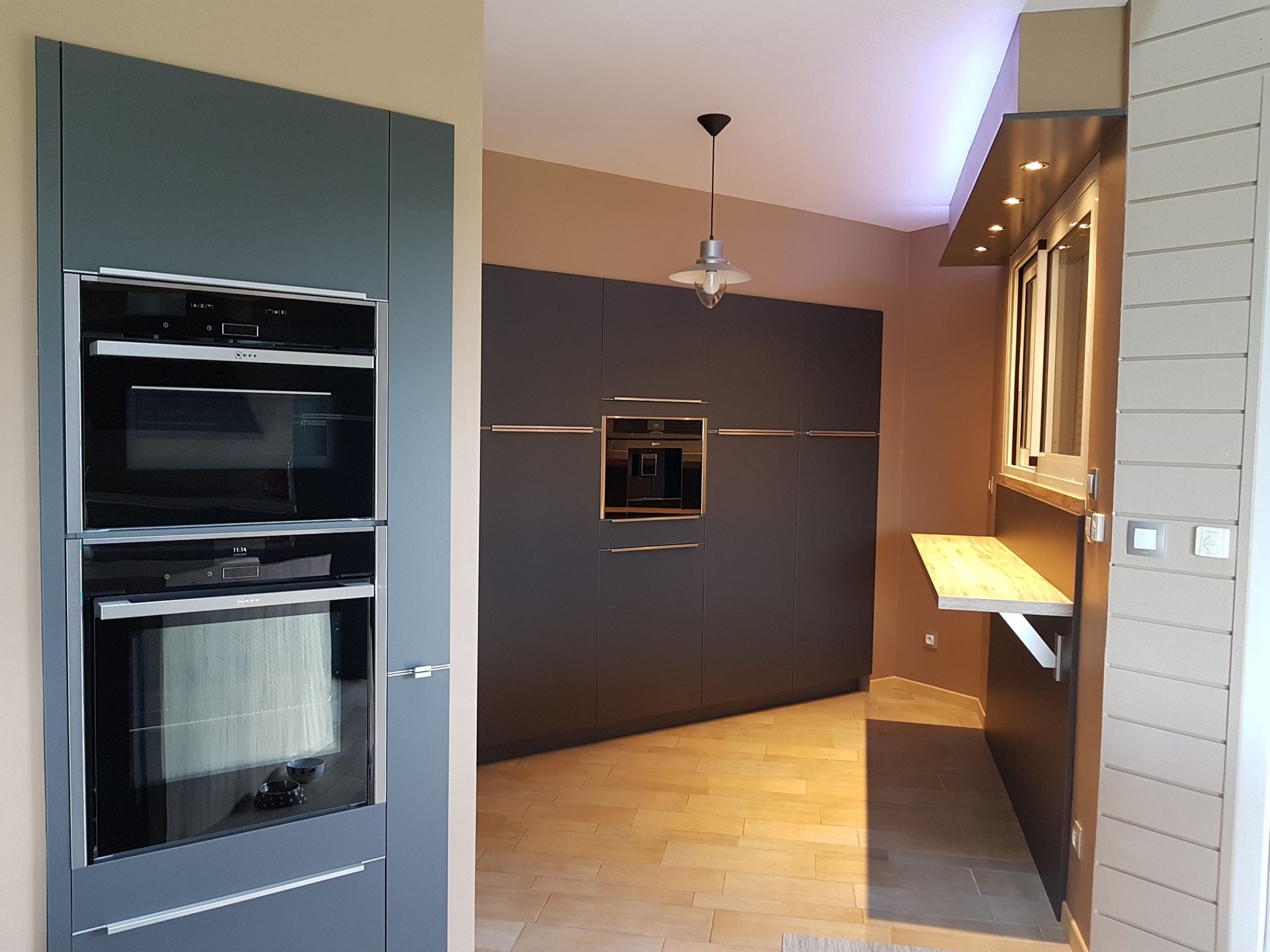 Cuisine moderne avec des armoires gris foncé, un four mural et un micro-ondes encastrés.