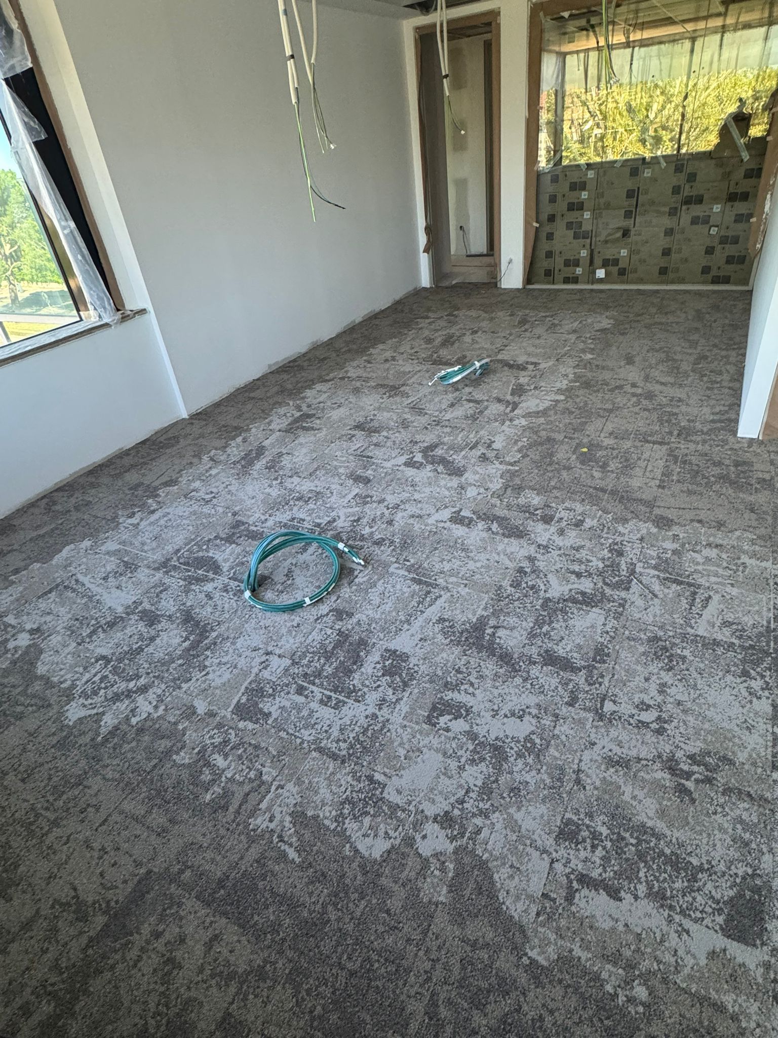 Habitación con alfombra nueva, ventana y puerta. Alfombra gris claro y blanca moteada.